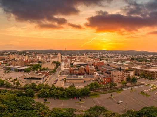 Aerial view of the city of Scranton at sunset. The sky is orange. There are clouds in the sky.